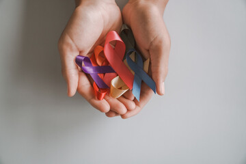 Hands holding color ribbons, world cancer day, World Autism Awareness Day concept
