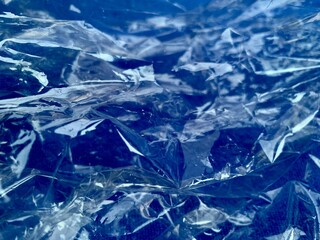 Clear crumpled reflective plastic on blue ground
