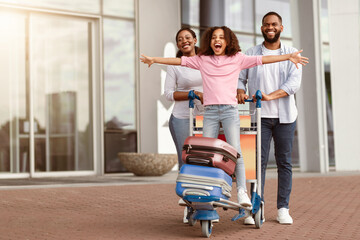 Family Trip Concept. Portrait of cheerful African American girl having fun and spreading hands,...