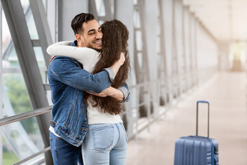 Long Awaited Meet. Happy Arab Man Hugging Girlfriend At Airport After Arrival, Joyful Middle...