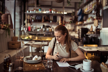 Waitress calculating restaurant expenses while working in a bistro