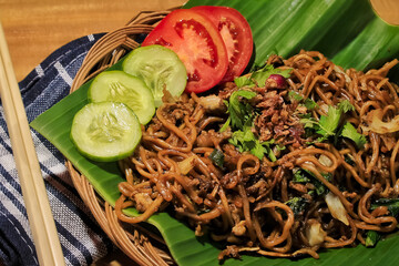 fried noodles served with banana leaves. fried noodles with cucumber and tomato. fried noodle is delicious food. fried noodles one of the most popular foods in asia