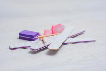 Manicure kit featuring nail files, buffer, sticks, and a brush on a light wooden background.