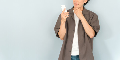 スマホを見て迷惑がる男性（迷惑電話・詐欺・ニュース）
