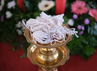 The sacred thread in a golden tray, a white raw thread used in religious ceremonies.