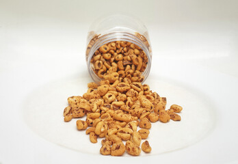 Golden puffed wheat grains spilling out of clear plastic jar isolated on white background. Organic and healthy cereal food. Honey air rice.
