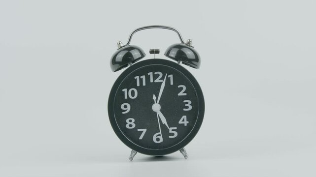 Close-Up of Black Analog Alarm Clock Ringing at 5 AM, 5 PM, Midnight, or Noon on White Background &ndash; Time Concept, Morning Routine, and Daily Schedule Footage