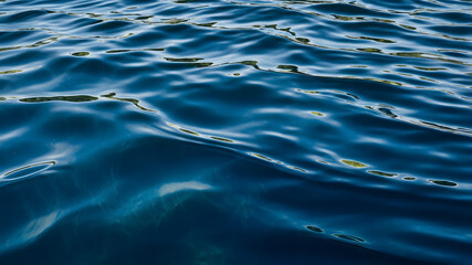 Deep blue water ripples reflect light, creating a serene scene perfect for background, meditation, or relaxation-themed projects
