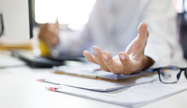 Close up shot, asian man working at desk in office and show outstretched hand with open palm, select focus