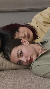 Vertical portrait of diverse female zoomers confidently looking at camera while resting on floor at home