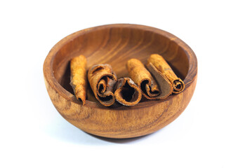 Cinnamon in a wooden bowl isolated on white background. Cinnamon bark is a spice obtained from the...