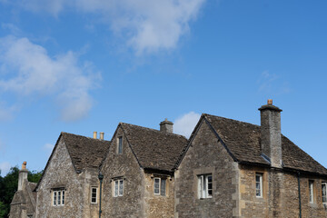End walls of heritage building homes with row of three gables under blue sky.