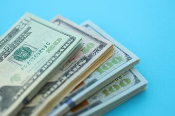 Big amount of hundred, fifty and twenty dollar bills in thick stack lies on bright blue color paper...