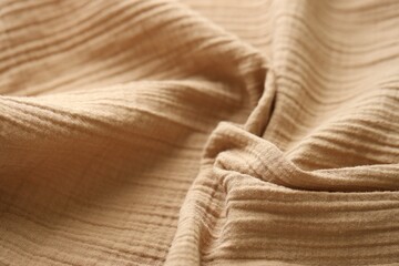 Texture of crumpled linen fabric under natural light in peach fuzz color