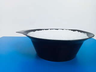 PP plastic pellets, virgin polypropylene polymer plastic granules poured from black cup into blue background, for product catalog design of plastic manufacturing industry company profile