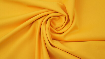Close-up of golden yellow cotton fabric showing a detailed woven texture, soft natural fibers, and a smooth textile surface perfect for design or background use.