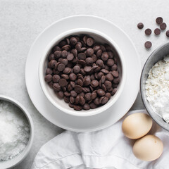 overhead view of mise en place for homemade chocolate chip cookies, ingredients for making chocolate chip cookies on a marble countertop	