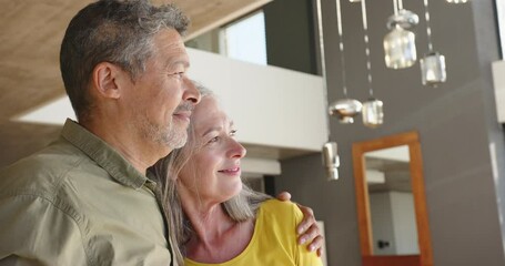 Smiling multiracial senior couple embracing and looking up, enjoying time together at home
