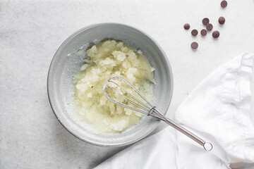Creaming oil and sugar in a grey bowl with a whisk, the process of making a cake and cookies, mixing oil and sugar to make a cake and cookies