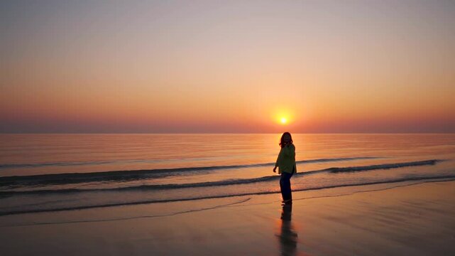 Silhouette of Indian girl walking at beach during sunset at Mandvi, Kutch, India. Tourist enjoying holidays at tropical beach. Travel and vacation concept.
