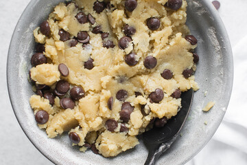 Overhead view of chocolate chip cookie dough, top view of homemade chocolate chip cookie dough in a bowl on a white background, process of making chocolate chip cookies