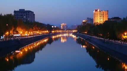 A serene city view with a riverfront reflecting the lights of urban buildings.