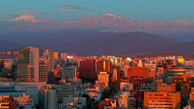 Aerial cityscape of Santiago de Chile, El plomo Hill rises over Las Condes residential buildings at Sunset