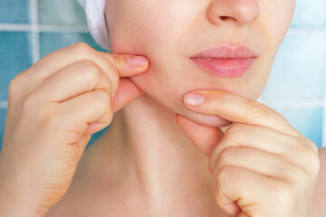 Portrait of young woman doing chin massage against background of blue tiles.