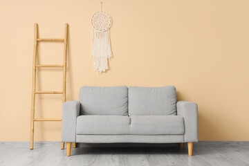 Grey sofa with ladder near beige wall in living room