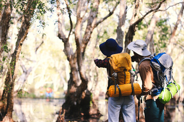 Naklejka premium Couple backpackers travel in the forest Use binoculars while hiking.