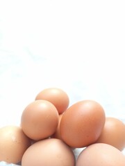 Heap of chicken eggs on white background. Farm products, natural brown eggs. Close up. Space for text. Selective focus.