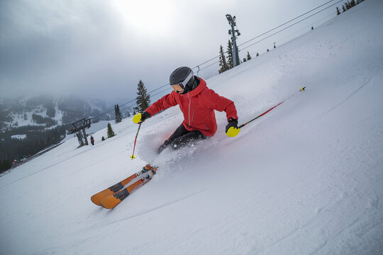Skier carving through fresh snow on a steep slope