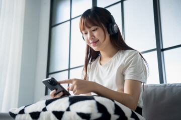 Asian woman listening to music, podcast relax on sofa