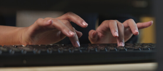 Close-up view of hands actively typing on a sleek black computer keyboard, capturing the essence of...