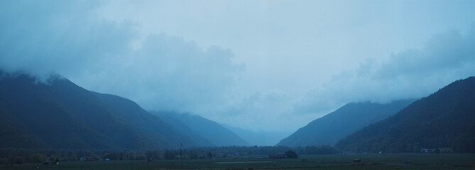 Moody blue mountain landscape with fog and rolling hills