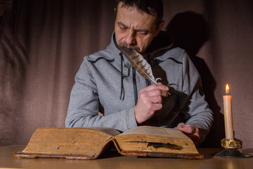 A European man reads an ancient book by candlelight.