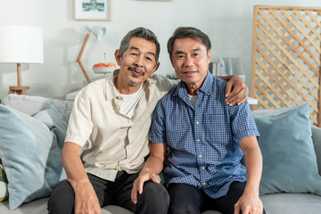 Portrait of Asian elderly man friend sitting on sofa in living room at home.
