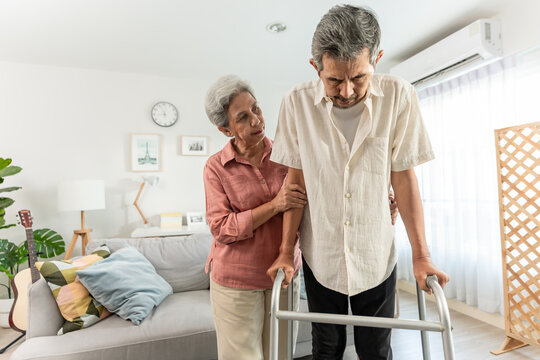 Asian attractive senior woman support elderly man walking with walker. - Powered by Adobe