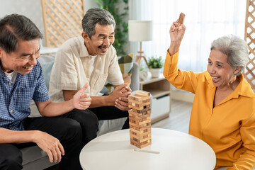 Group of senior friend play game with wooden block in living room at home.