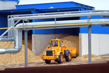 Front loader operating in woodchip storage yard at manufacturing facility. Bulldozer handling...