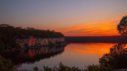 Obraz premium Stunning Sunset Reflection Over Calm Lake Surrounded by Forest