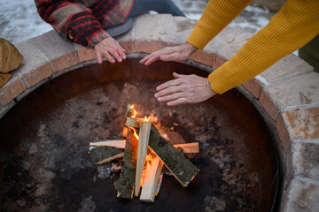Close up of hands above flames. Fire in garden fire pit.
