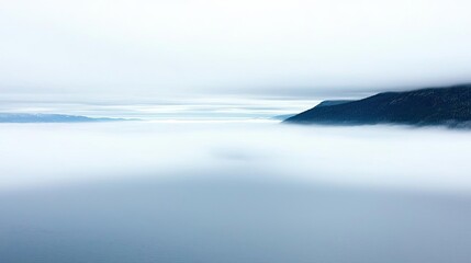 Fototapeta premium Blurred abstract background concept. A serene foggy landscape with soft clouds enveloping the hills and distant horizon.