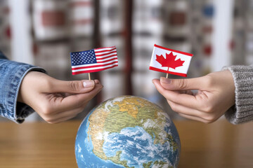 Friendship and unity: hands holding miniature american and canadian flags over globe