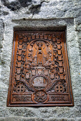 Intricately carved wooden religious panel featuring Nossa Senhora Aparecida, surrounded by decorative elements, set against the stone wall of the Salt Cathedral of Zipaquira, Colombia.