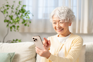 リビングでスマホを使うシニアの日本人女性