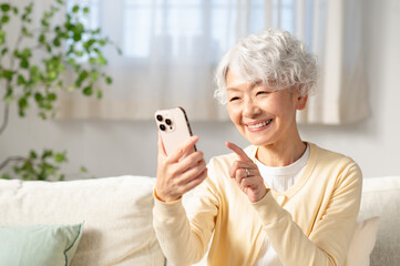 リビングでスマホを使うシニアの日本人女性