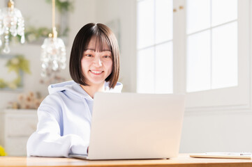 リビングでノートパソコンを使う若い日本人女性