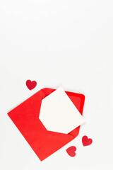 Top view of red envelope, white card on white background. Valentine's day, red hearts, love. Post flat lay, copy space.