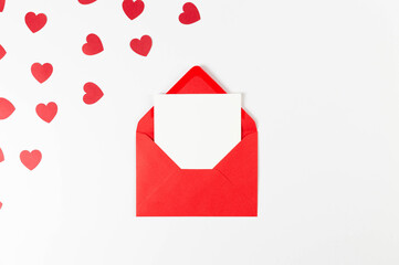 Top view of red envelope, white card on white background. Valentine's day, red hearts, love. Post...